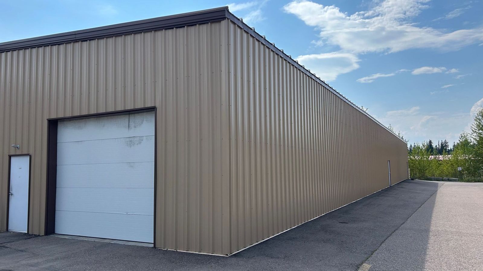 The tan steel Mountain View Boat Storage building on MT Highway 40 West in Columbia Falls, Montana, with a white roll-up door