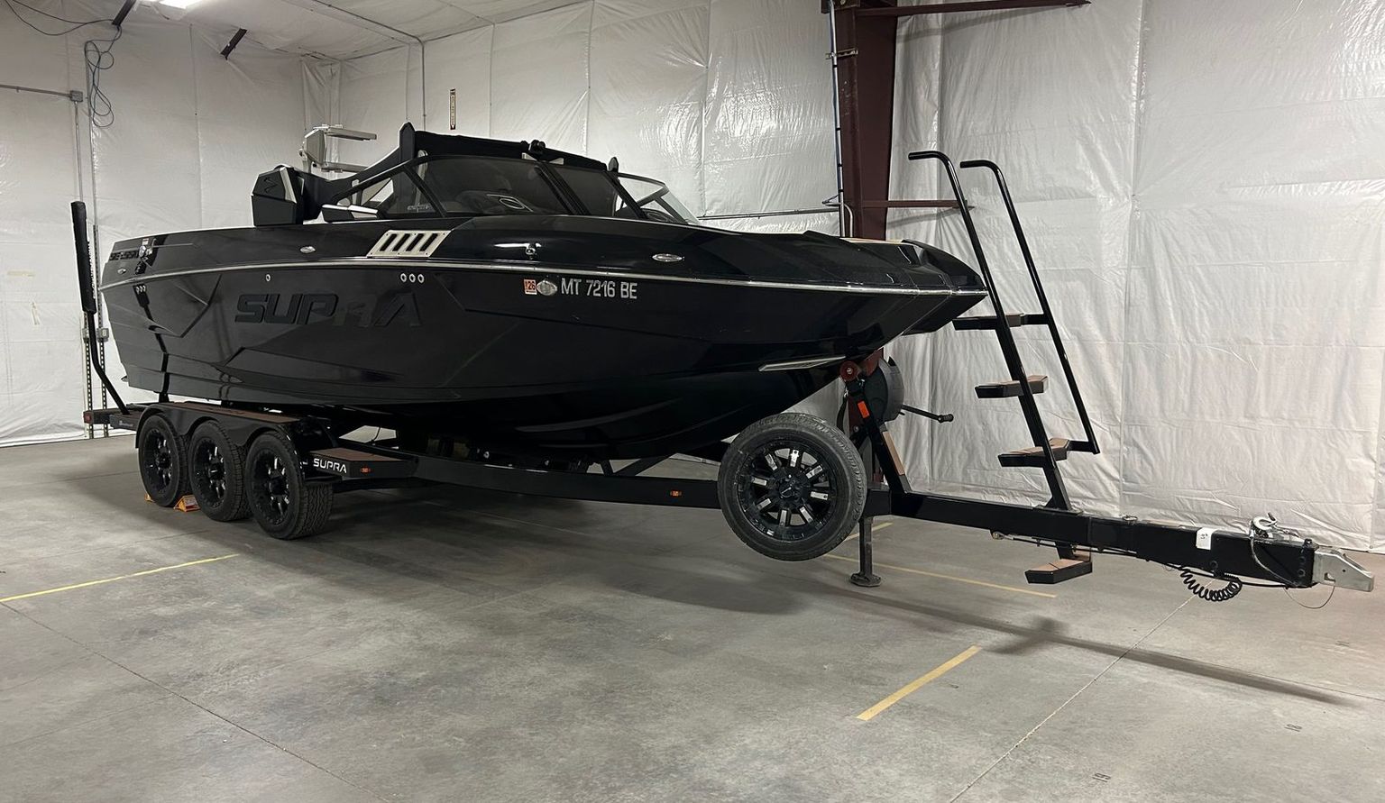 A wakeboard boat on its trailer in a marked bay inside the heated Mountain View Boat Storage building in Columbia Falls, Montana
